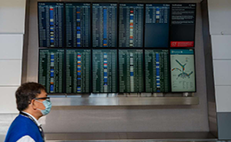 airport employee walks past arrival and departure screens